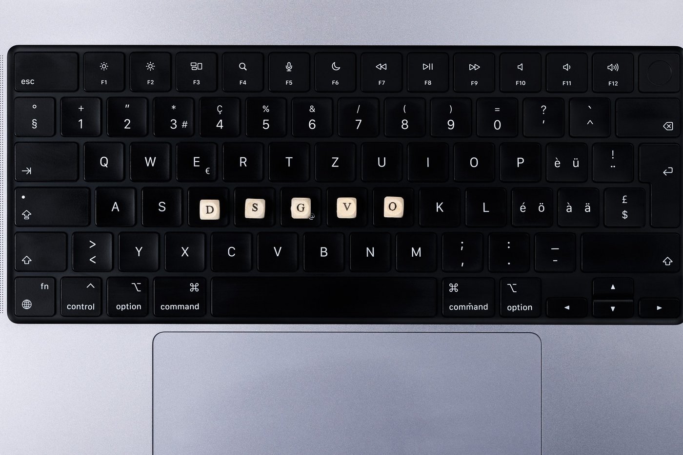 Studiofotografie eines Notebooks aus der Vogelperspektive. Auf der Tastatur sind Buchstabenwürfel zu sehen, welche das Wort DSGVO aufzeigen.