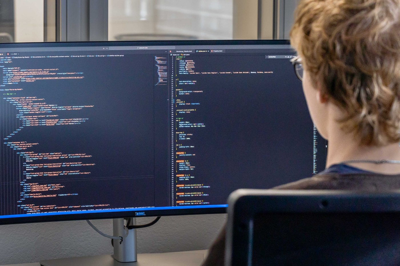 Fotografie eines Lehrlings, welcher vor dem PC-Monitor sitzt und eine Webite entwickelt.
