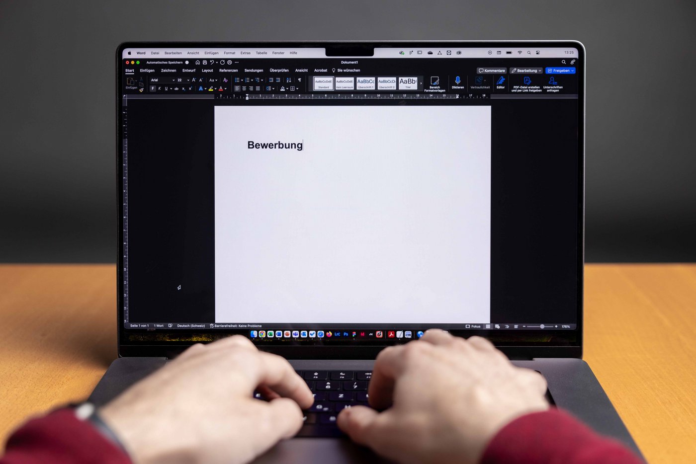 Frontaufnahme eines Notebook-Monitor und Händen, welche einen Text auf der Tastatur eingeben.