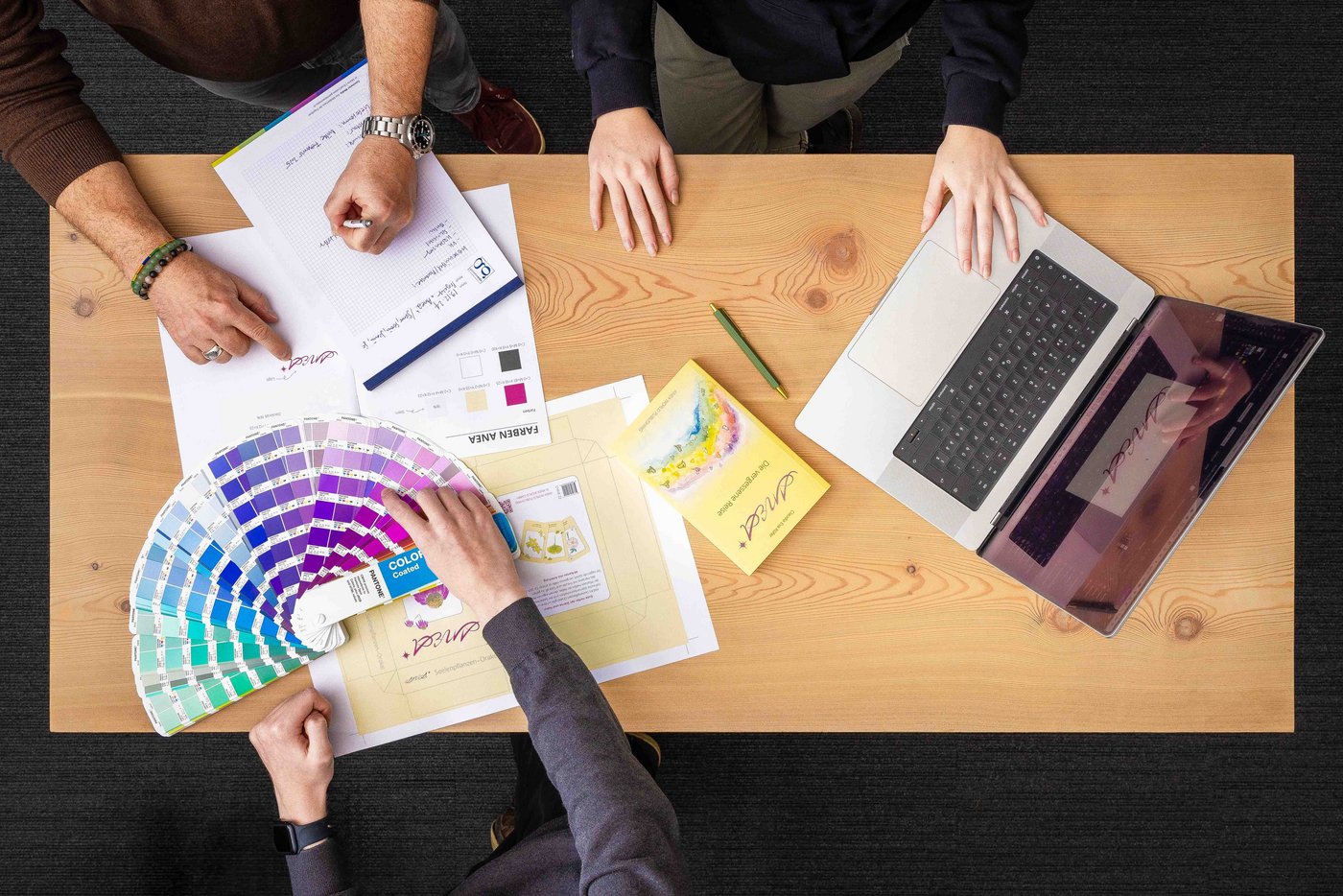 Fotografie von Oben, bei der ein Team aus Polygrafen ein Design besprechen
