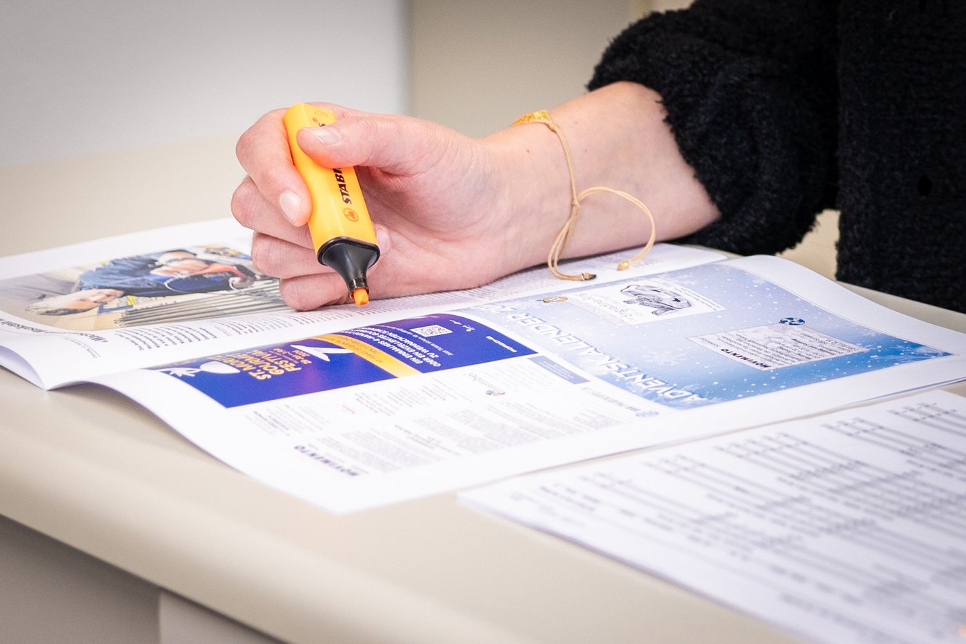 Nahaufnahme Einer Hand beim Markieren von Text einer Zeitung mittels Stabilo Boss.